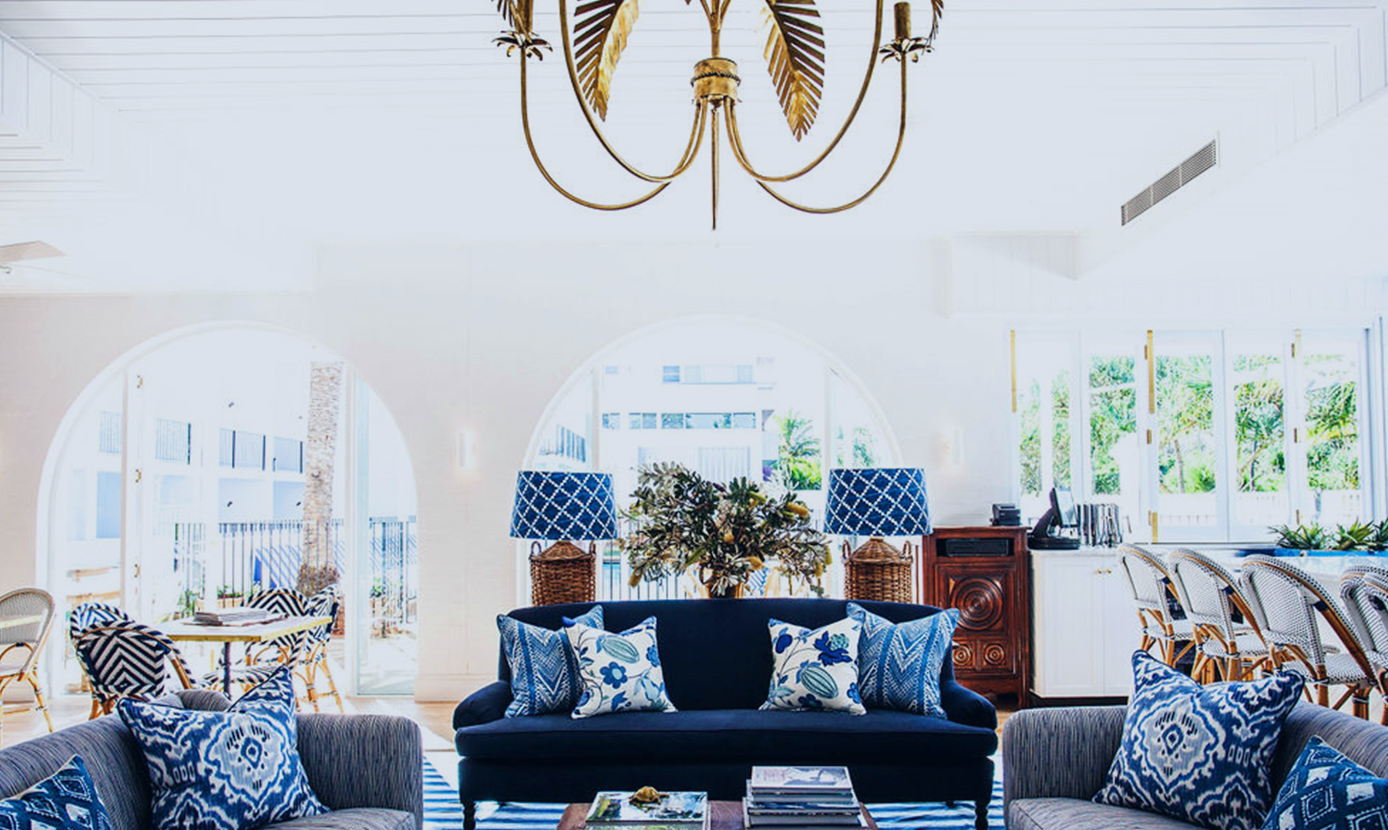 Hotel lounge with a navy sofa, blue cushions and a gold palm chandelier