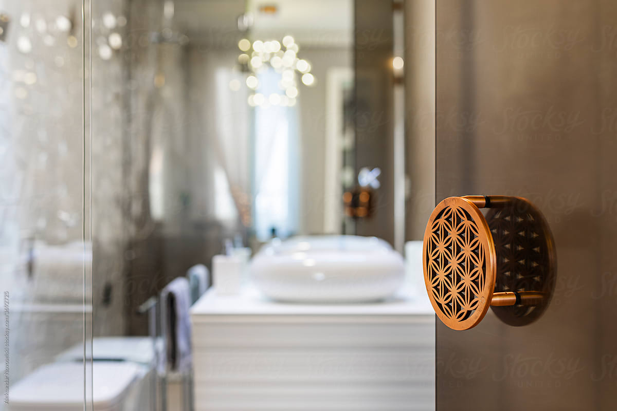 Copper door handle with geometric cut-out pattern in a luxury hotel bathroom