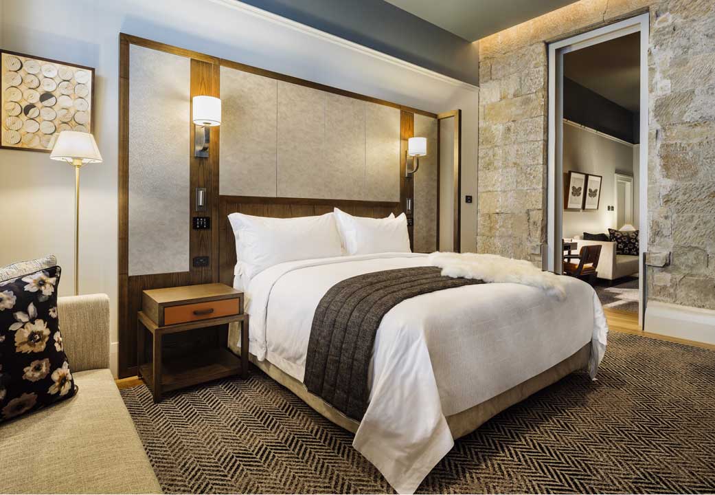 Luxury hotel bedroom with white linen and a dark throw